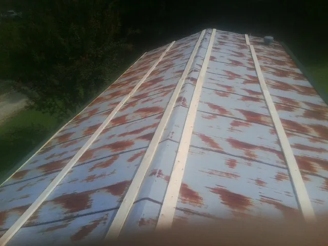 Rusted metal roof panels with new wood purlins before replacement — Storm Damage Roof Repair in North Prairie by Roofing Brothers