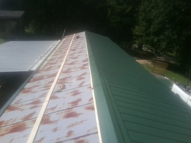 Old rusted panels beside newly installed green metal roofing — Wind Damage Roof Repair by Roofing Brothers in North Prairie