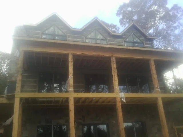 Dormers and porch framing on a large log home under construction — Roof Coating work by our crew in North Prairie