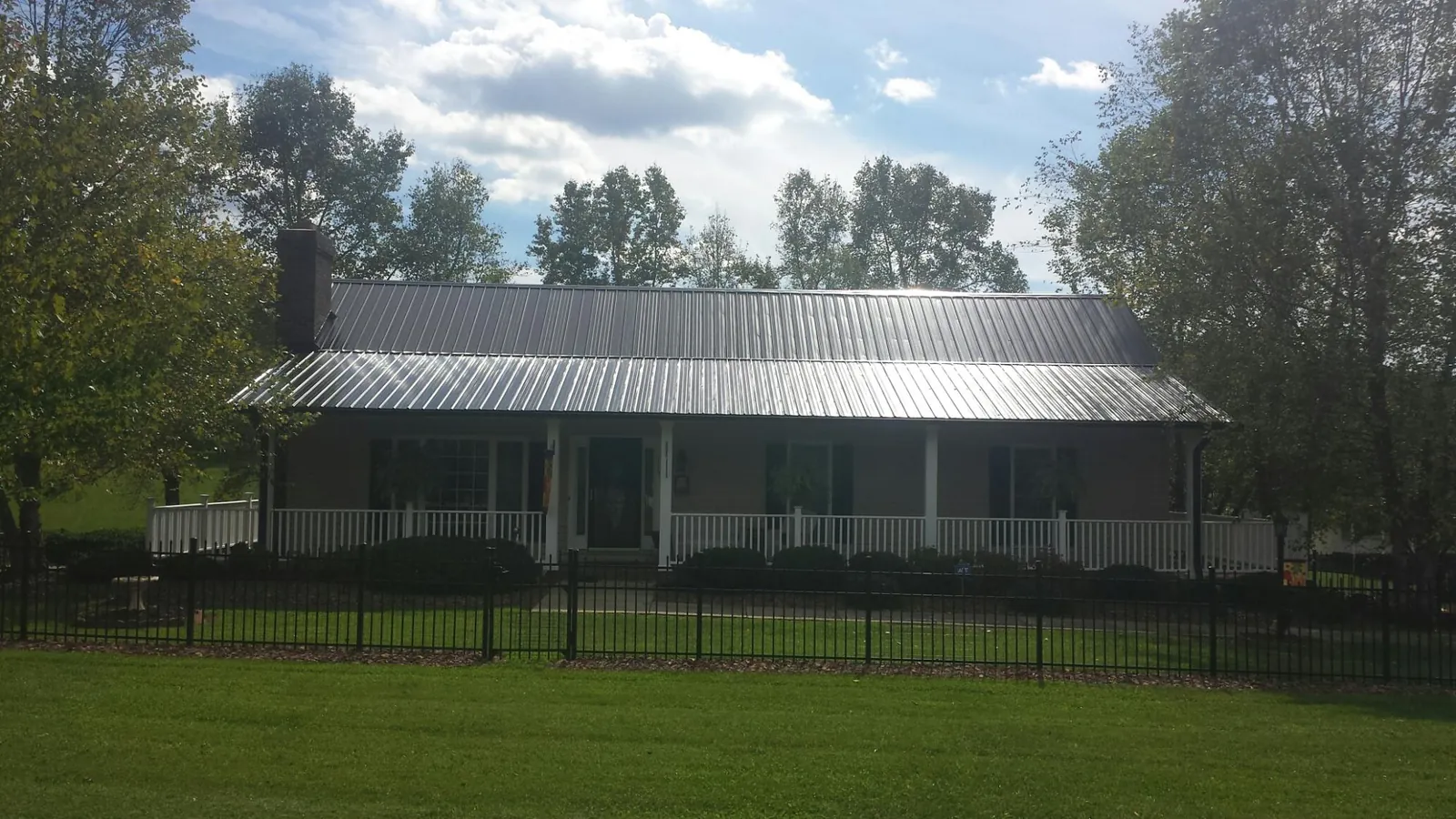Gray metal roof on a brick ranch with a full width front porch in North Prairie