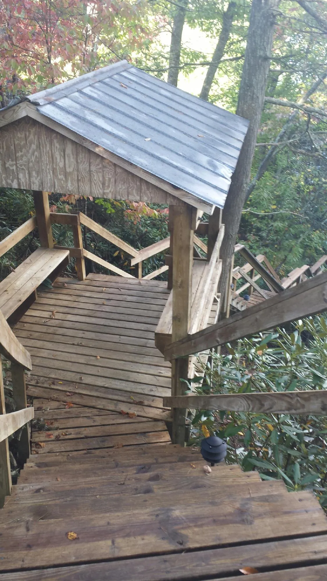 Metal roofed shelter over wooden steps on a wooded walkway — Skylight Repair & Installation work by our crew in North Prairie