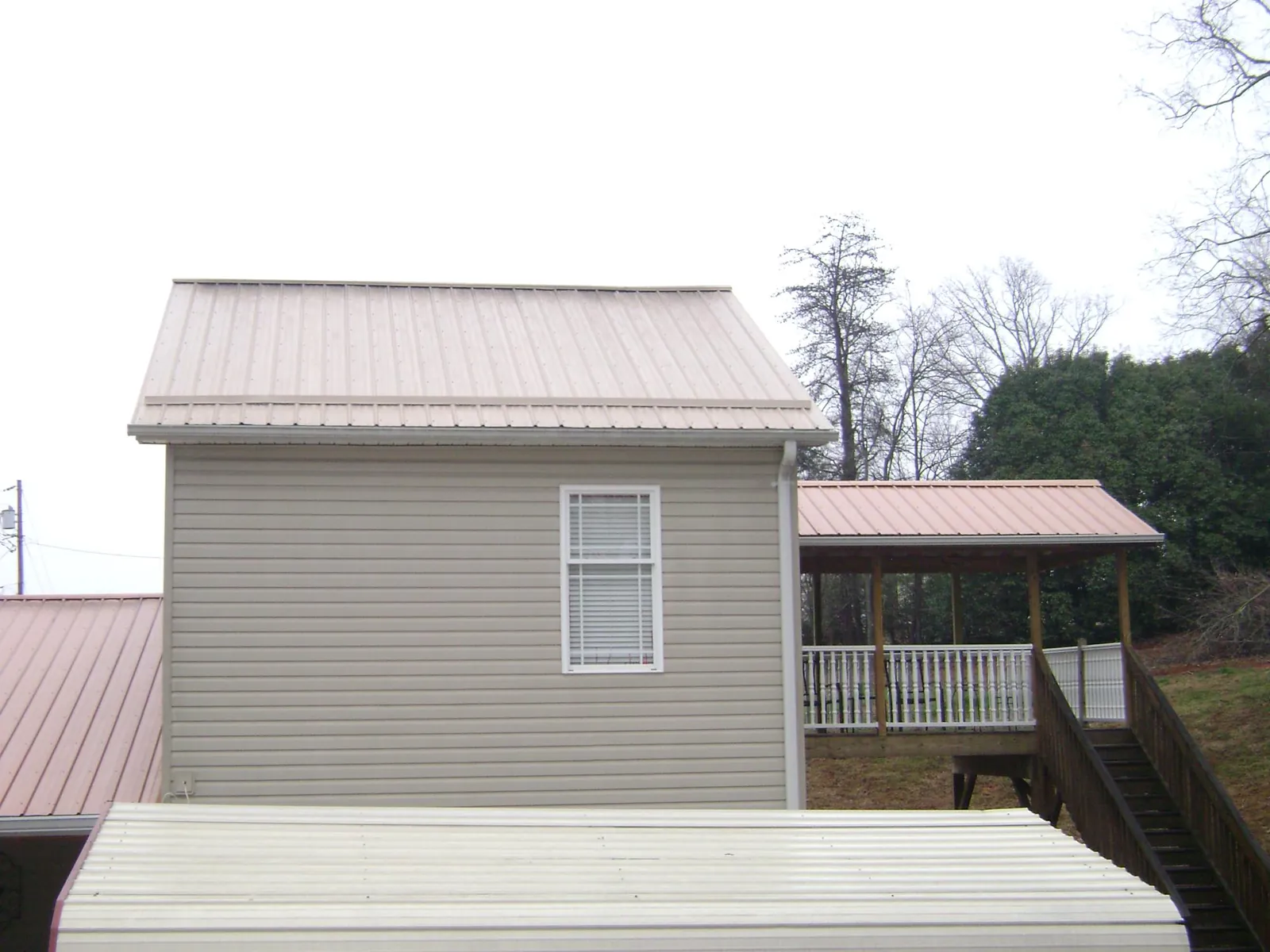 Tan metal roofs on a two story addition and attached porch, from a Roof Replacement job in North Prairie