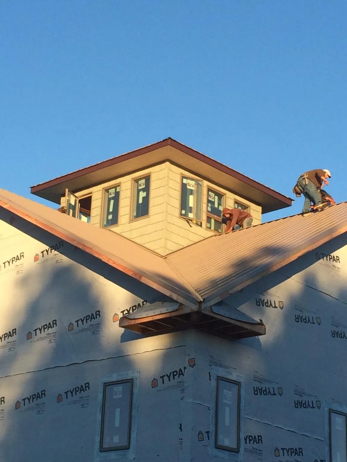 Roofers working around a rooftop cupola on a new metal roof at sunset — Roof Waterproofing in North Prairie by Roofing Brothers